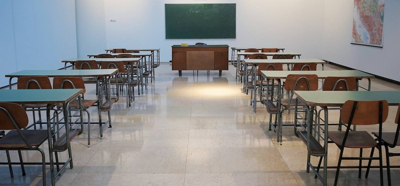 Empty classroom with rows of desks facing a chalkboard